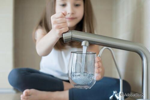 Ein Kind füllt ein Glas am Wasserhahn. Ein Kind füllt ein Glas am Wasserhahn.