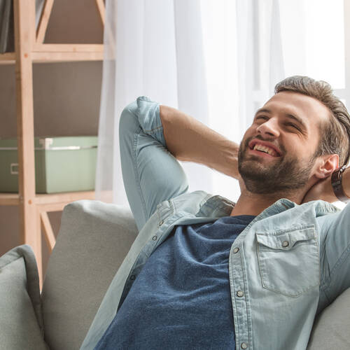 Ein glücklicher Mann entspannt sich auf einer Couch